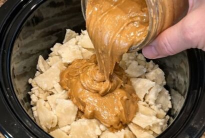 Thumbnail for Dump jar of creamy peanut butter over frozen raw pie crust pieces, along with 3 other ingredients, into slow cooker for a treat that’s my default when